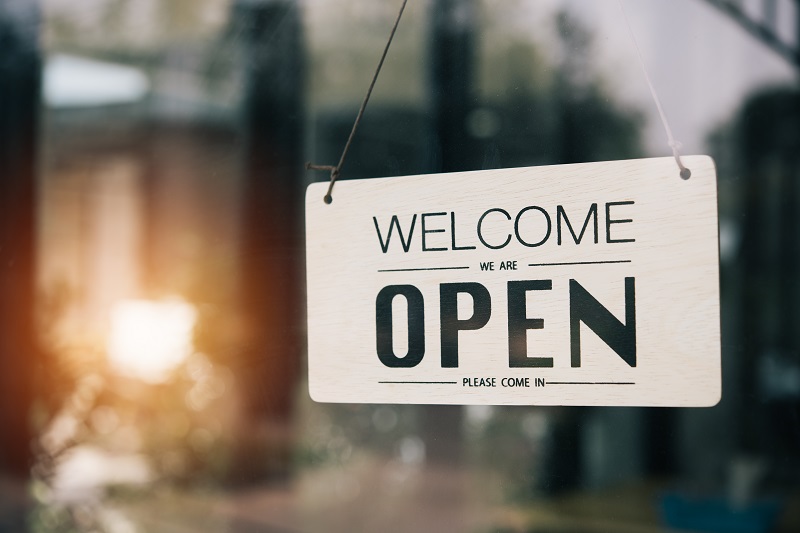 a sign on a window. Containing the words: welcome we are open come in