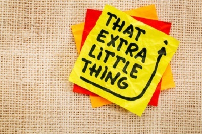 a yellow and red note with black writing on it. Containing the words: that extra little thing