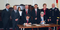 a group of people in suits signing papers.