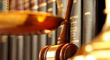 a gavel and scales in front of books.