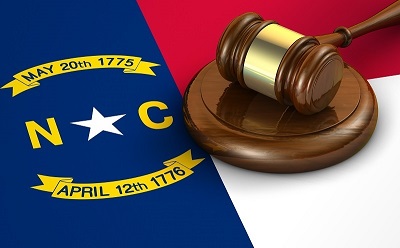 a gavel on a block next to a flag. Containing the words: may 20th 1775 NC April 12th 1776