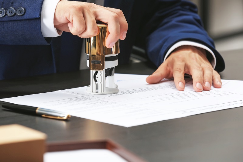 a person's hand stamping a document.