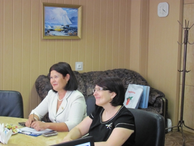 women sitting at a table with a laptop.