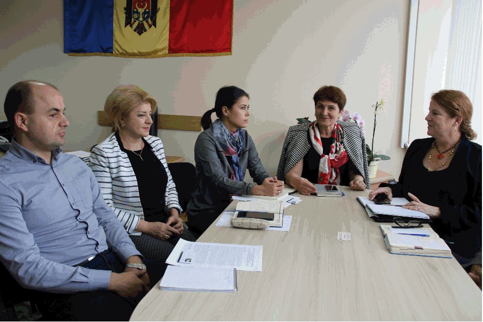 A group around a table discussing Moldova with a Moldavian flag hung on the wall.