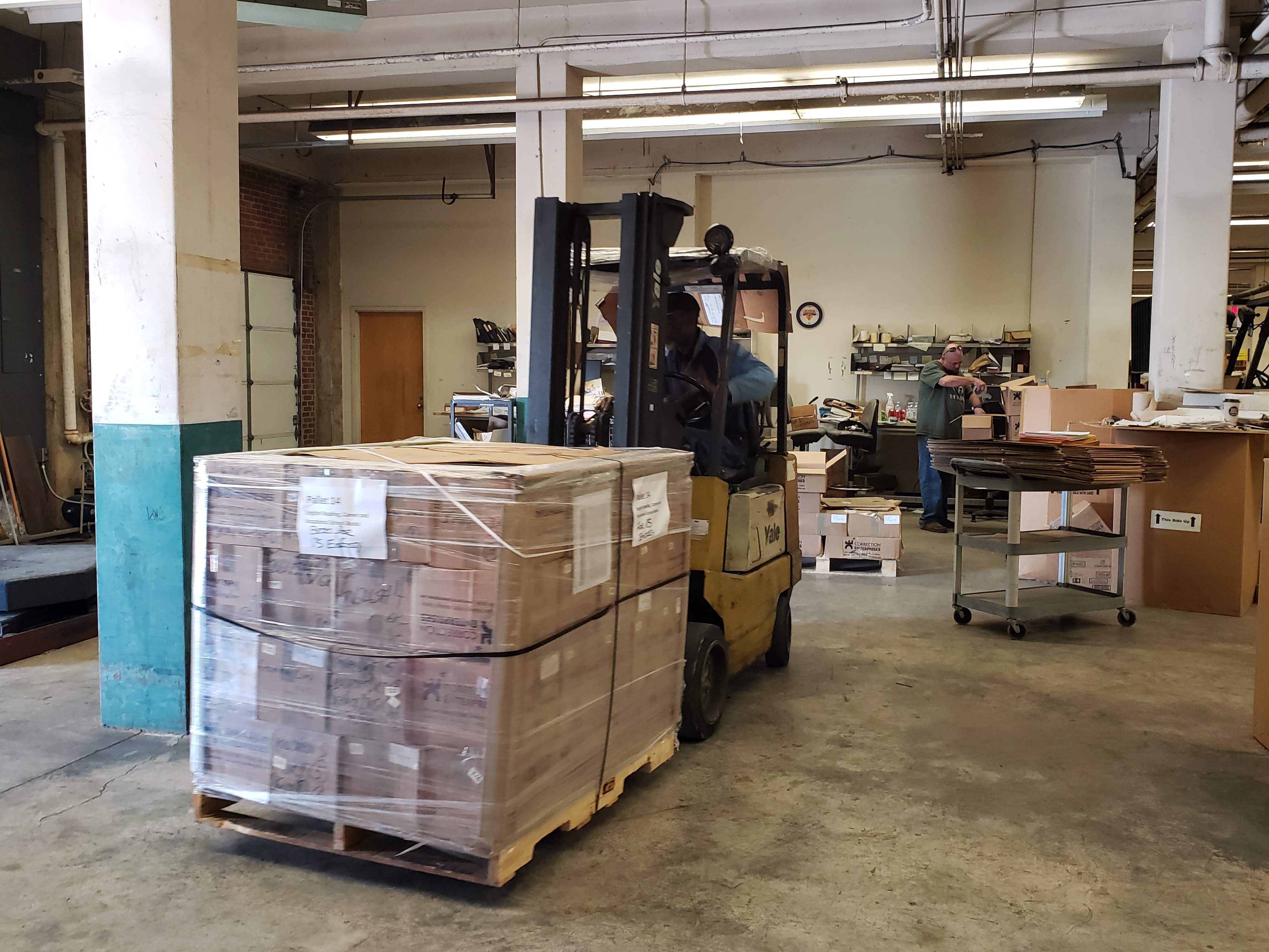 a person driving a forklift in a warehouse.